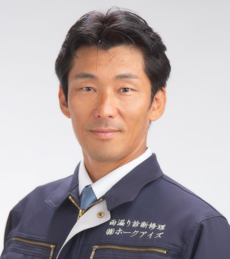 雨漏り診断士よねだの作業服姿：㈱ホークアイズ代表としての歴史と誠実な笑顔のポートレート