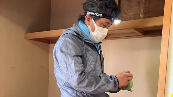 「木造住宅の天井裏へ潜入する精密雨漏り診断：ヘッドライトを装着し、見えない箇所の不具合を徹底追及する準備風景