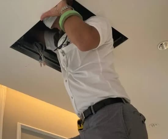 岐阜県の新築歯科医院にて、雨漏り原因特定のため診療室の天井点検口から天井裏へ侵入調査を行う様子